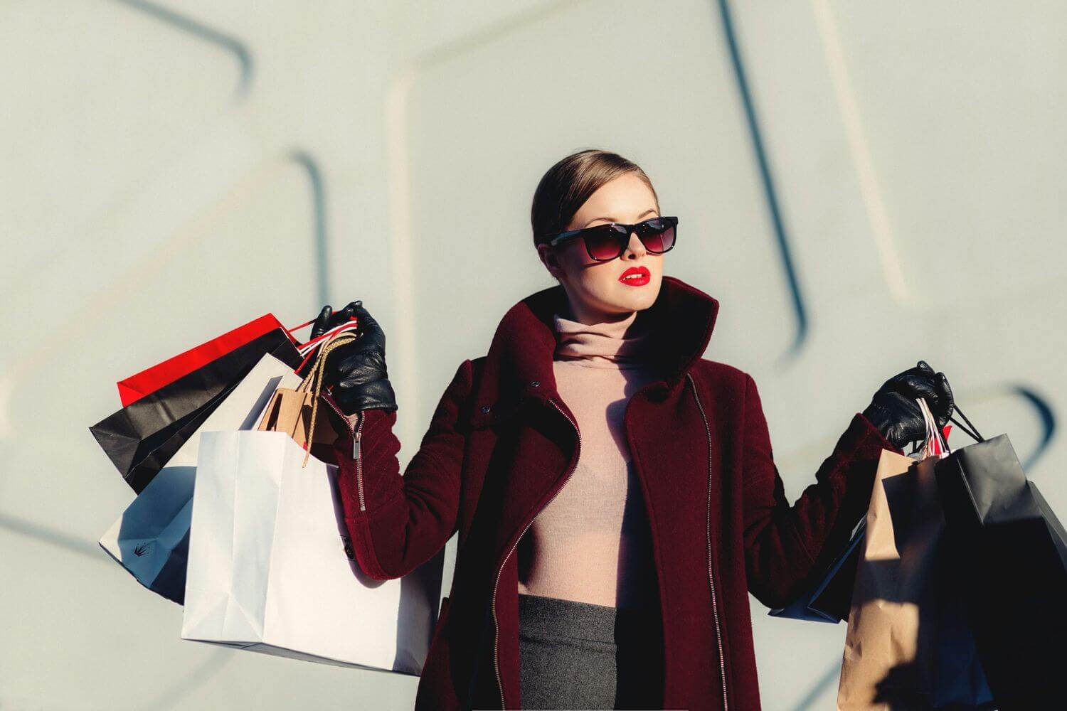 a woman with sunglasses and red liptsick holding multiple shopping bags