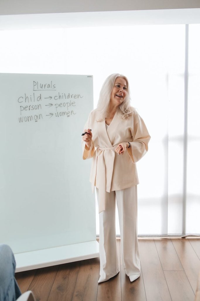 an old teacher standing in front of her class teaching english