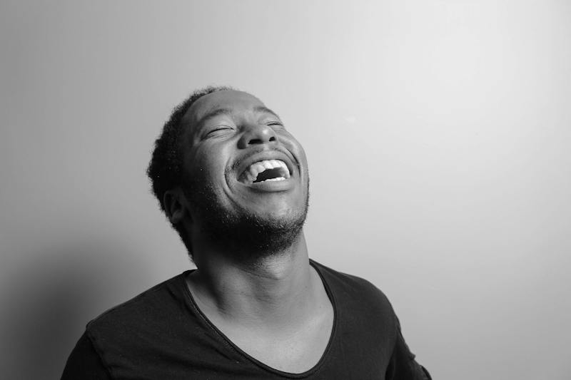 Guy in t shirt against a white wall laughing
