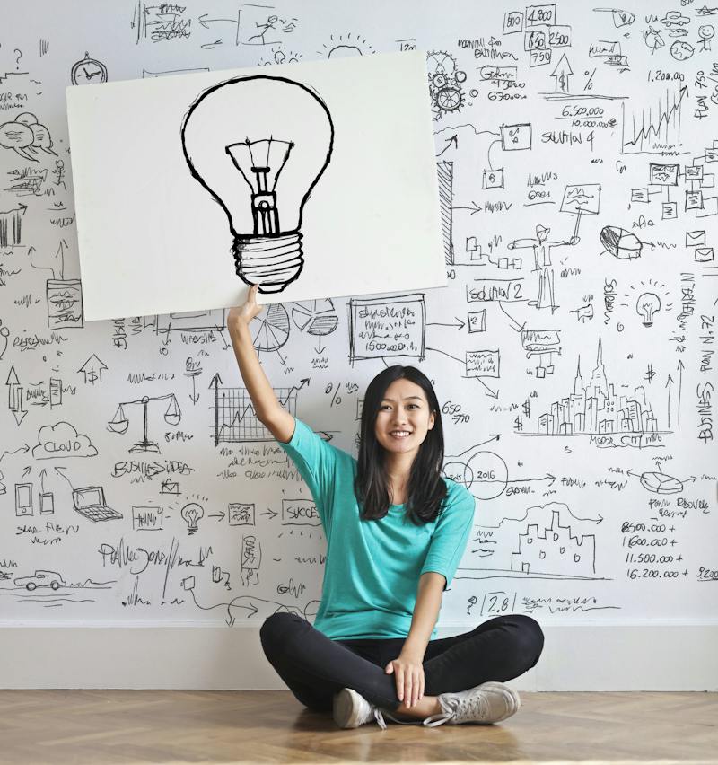 Smiling girl holding up a lightbulb sign