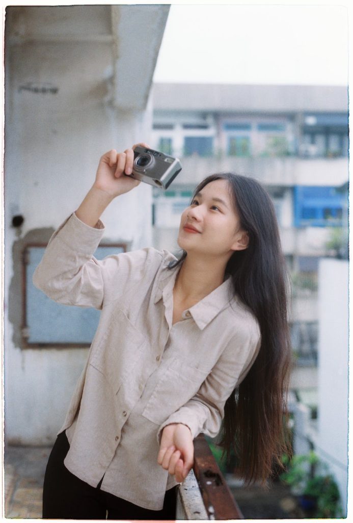 Girl in red lipstick taking a photo on a balcony