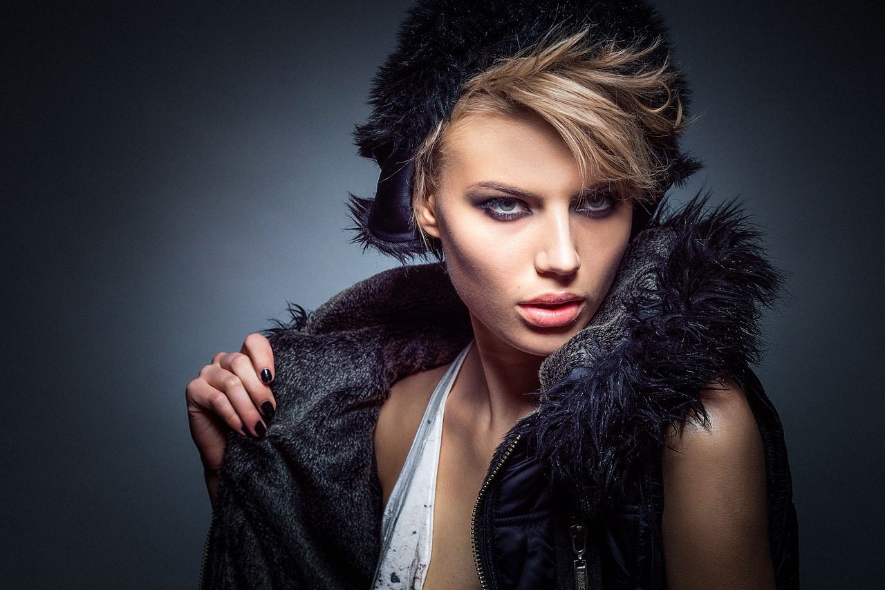 A beautiful model in a black cap and vest made of wool looking into the camera