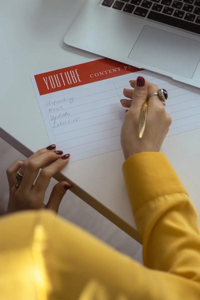 A woman planning out her Youtube content using a pen and paper with the title "YouTube content planner"
