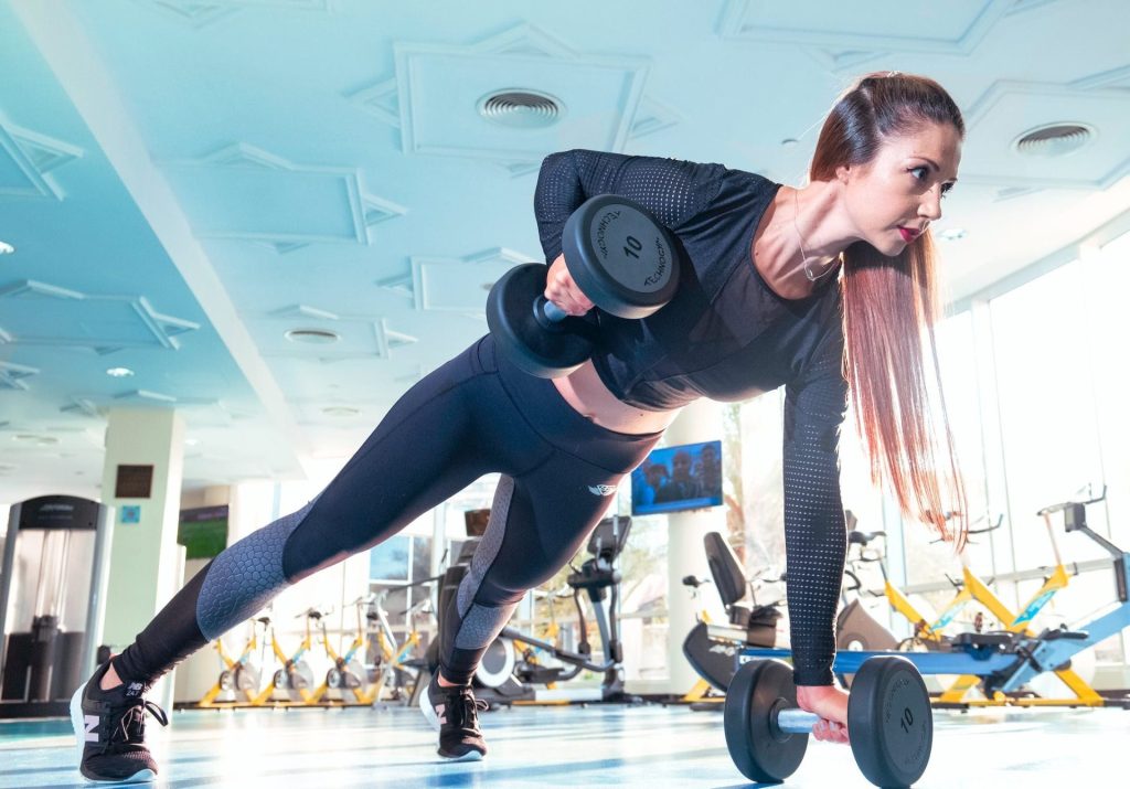 woman working out in a gym doing dumbell rows on the floor