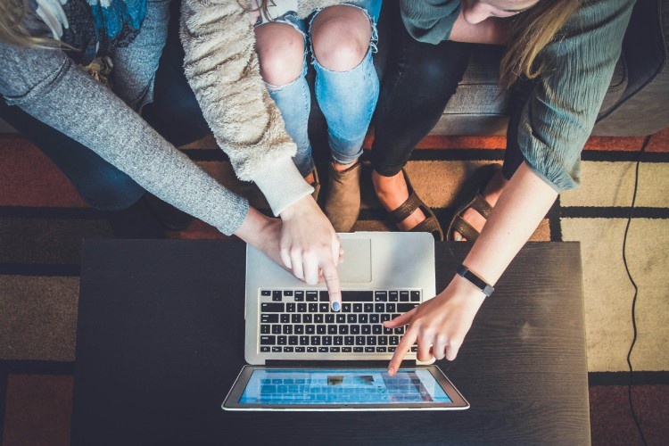 people crowded behind a laptop screen pointing