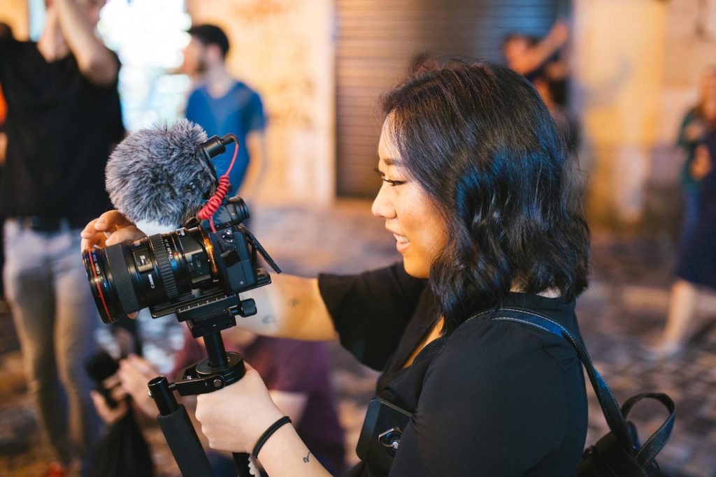 Woman vlogging her life holding camera while outdoors
